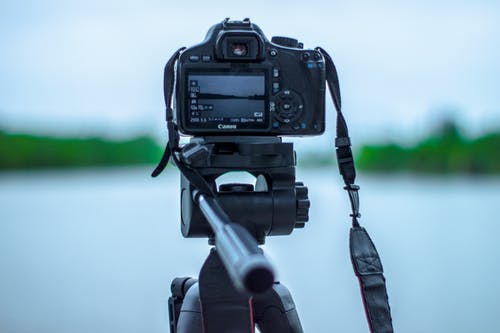 黑色佳能相机的选择性聚焦照片，位于水体前的三脚架上 · 免费素材图片
