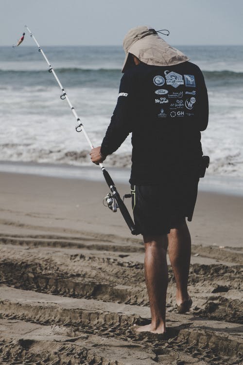 黑色长袖上衣，附近海滩举行白色钓鱼竿的人 · 免费素材图片