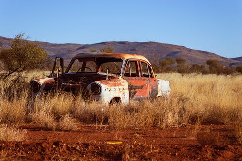 锈蚀的老式白色和红色轿车在棕色草地上的照片 · 免费素材图片