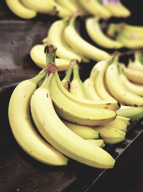 一堆香蕉在黑色表面上的选择性聚焦照片 · 免费素材图片