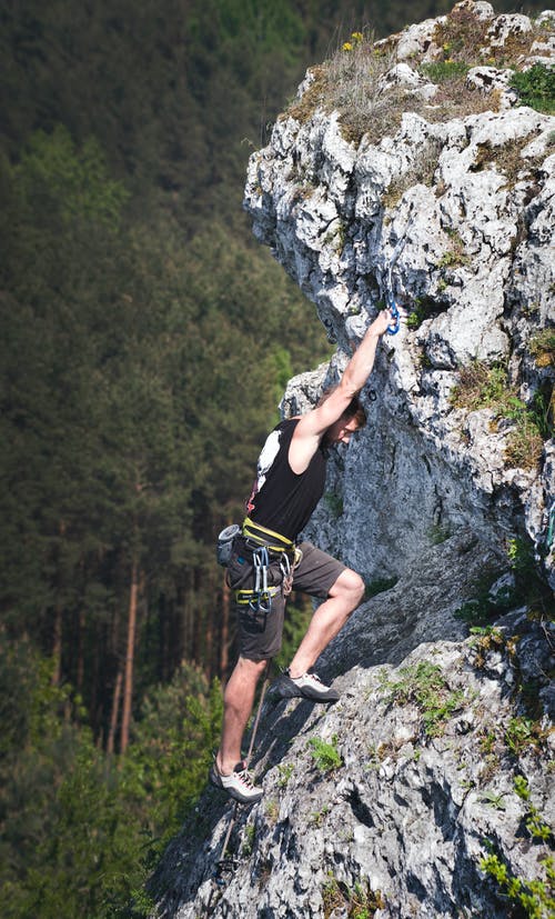 男人穿着黑色背心和棕色短裤攀岩 · 免费素材图片