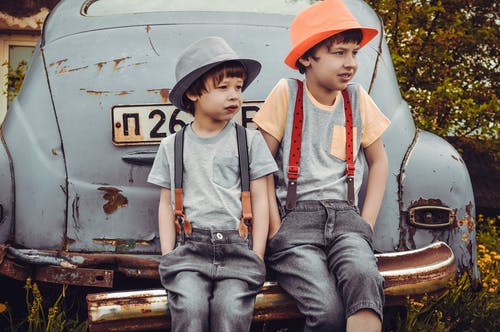 两个男孩坐在汽车保险杠上 · 免费素材图片