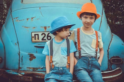 两个男孩坐在蓝色大众甲壳虫轿跑车的后保险杠上 · 免费素材图片