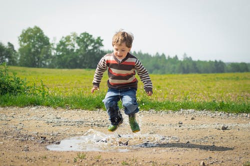 白天在草丛附近跳跃的男孩 · 免费素材图片
