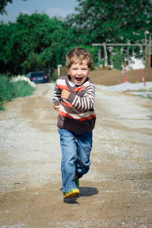 男孩穿着红色，棕色和白色的条纹毛衣跑步照片 · 免费素材图片