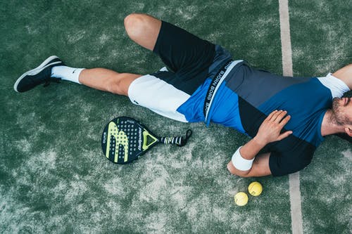 男子躺在绿色的网球旁边 · 免费素材图片
