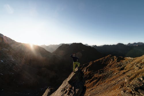 站在岩石上面对山顶的人 · 免费素材图片
