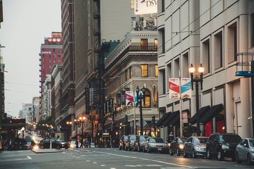 白色大厦旁边的公路上的汽车 · 免费素材图片