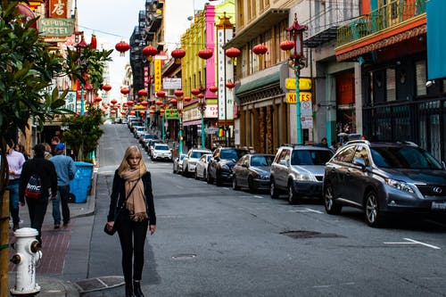 女人穿着黑夹克走在路上 · 免费素材图片