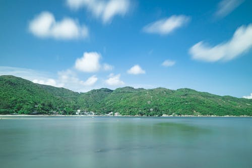 水体前的山覆盖的树木 · 免费素材图片