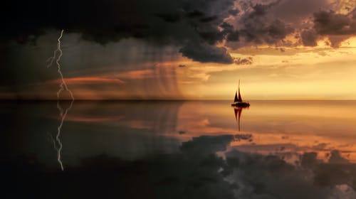 日落期间船在水面上的剪影摄影 · 免费素材图片