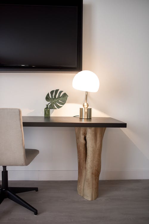 棕色木制办公桌上的不锈钢底座白色底纹台灯，靠近粉刷成白色的墙面墙上的平板电视 · 免费素材图片