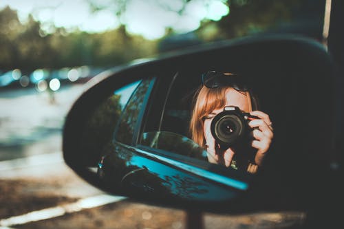 女人通过镜子取相机的选择性焦点摄影 · 免费素材图片