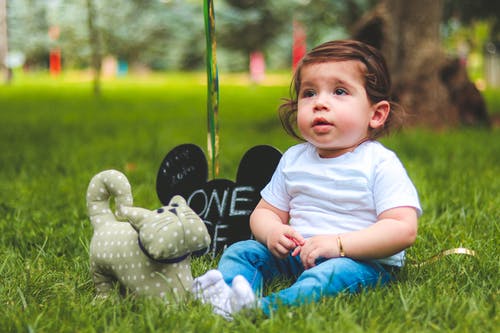 婴儿坐在绿色草地上的景深摄影 · 免费素材图片
