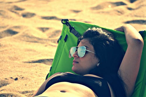 白天躺在沙滩旁边的床上的女人穿着比基尼 · 免费素材图片