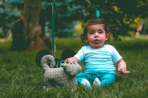 在灰色猫毛绒玩具旁边的孩子穿着青色t恤和青色裤子 · 免费素材图片