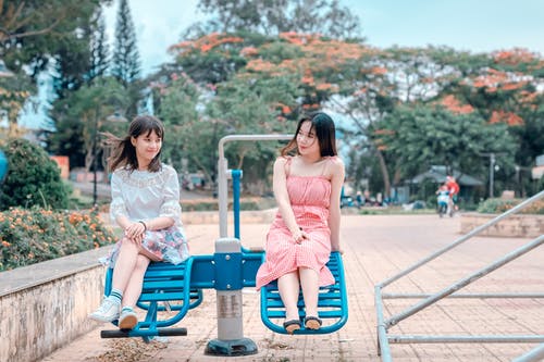 两个女人坐在蓝色公园骑 · 免费素材图片