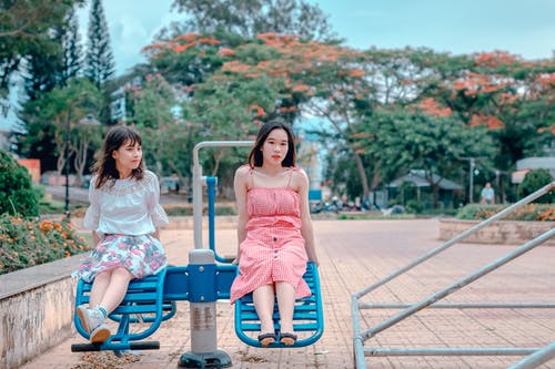 两个女人坐在公园骑 · 免费素材图片