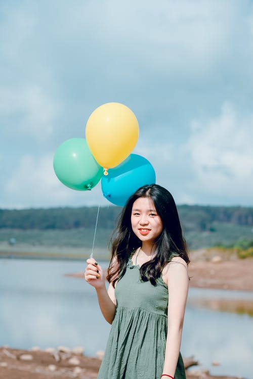 绿色无袖上衣拿着气球的女人 · 免费素材图片