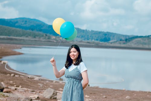 女人在海边拿着气球附近 · 免费素材图片