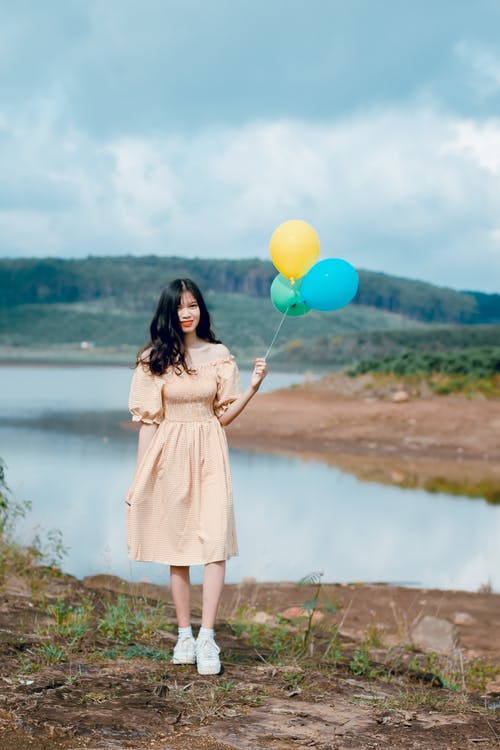 女人拿着气球的浅焦点摄影 · 免费素材图片