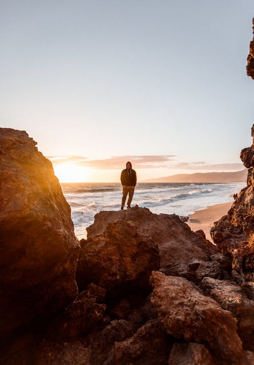 一个人站在一块岩石上的摄影 · 免费素材图片