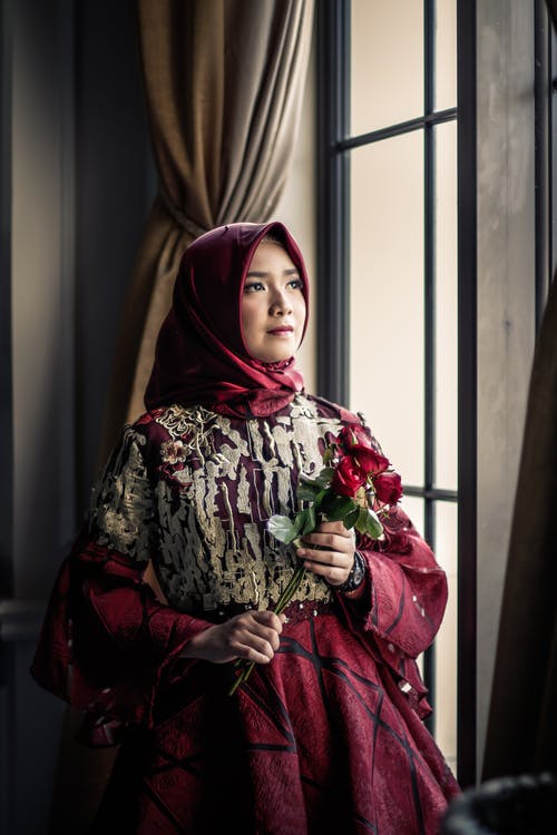 在室内举行红玫瑰的粉红色礼服的女人 · 免费素材图片