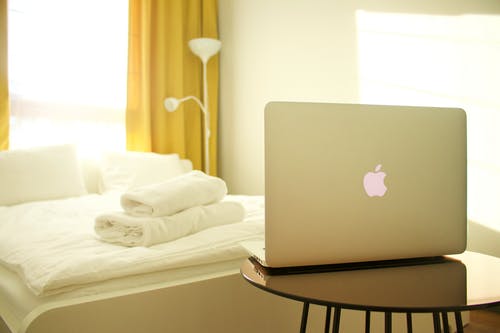 Macbook Air面对白床的木桌上 · 免费素材图片