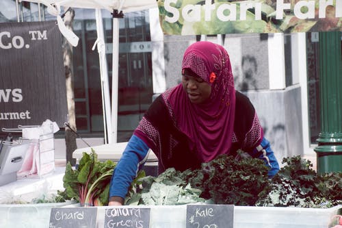 紫色头巾站在蔬菜前的女人 · 免费素材图片