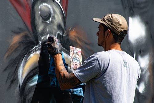 男人在墙上穿灰色圆领衬衫绘画 · 免费素材图片