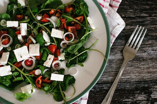 灰色不锈钢叉旁边的白色陶瓷板上的蔬菜色拉 · 免费素材图片