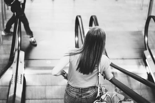 女人在自动扶梯上的单色摄影 · 免费素材图片
