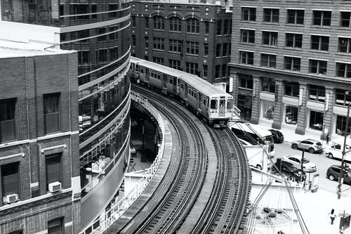 建筑物附近铁路上火车的灰度摄影 · 免费素材图片