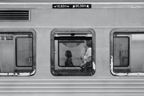 女人站在火车里面的灰度摄影 · 免费素材图片