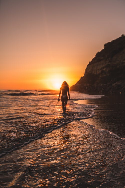 在黄金时段比基尼在山后水体上的女人 · 免费素材图片