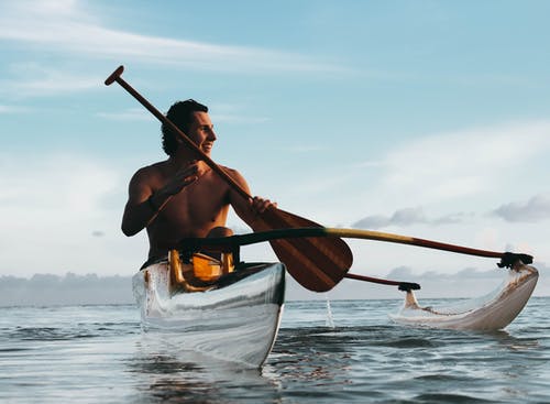 男子骑着小船，拿着棕色的桨 · 免费素材图片
