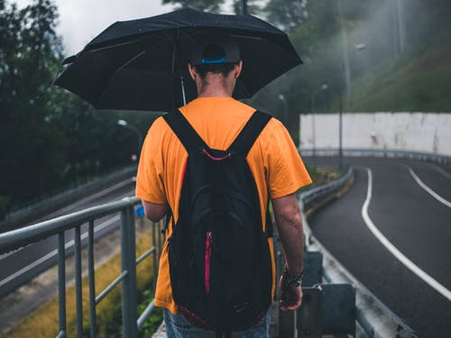 男人穿着橙色衬衫拿着黑色的雨伞 · 免费素材图片