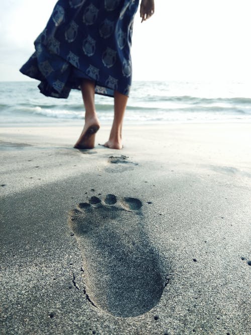 在海边赤脚行走的女人的照片 · 免费素材图片