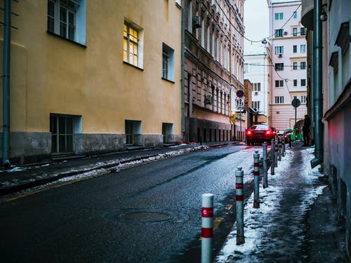 黑车穿越建筑物之间的柏油路 · 免费素材图片