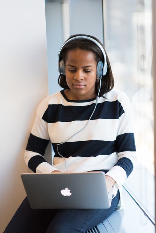 女人通过使用macbook的耳机听 · 免费素材图片