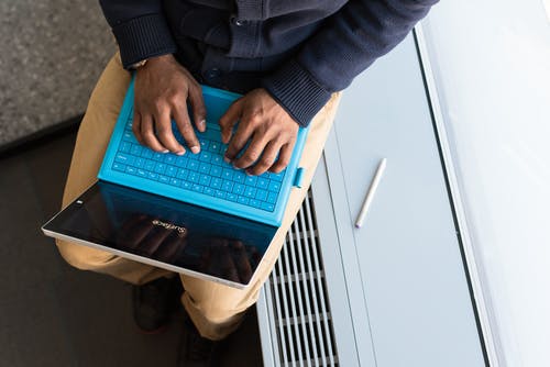 在蓝色便携式计算机上键入的人 · 免费素材图片