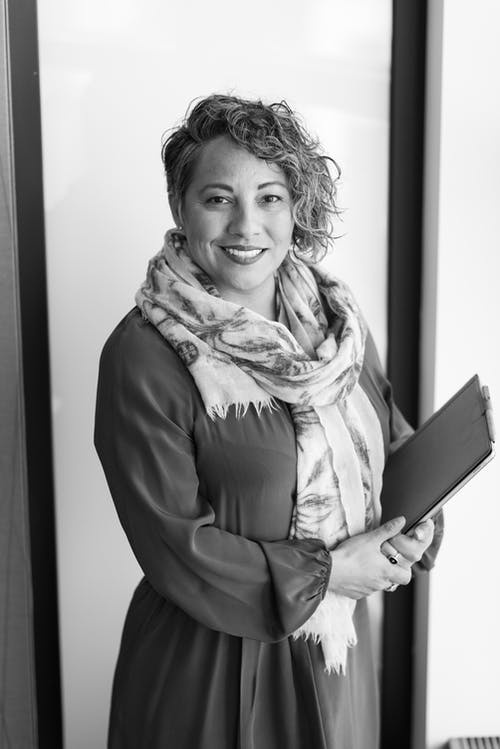 女人抱着平板电脑站在墙附近 · 免费素材图片