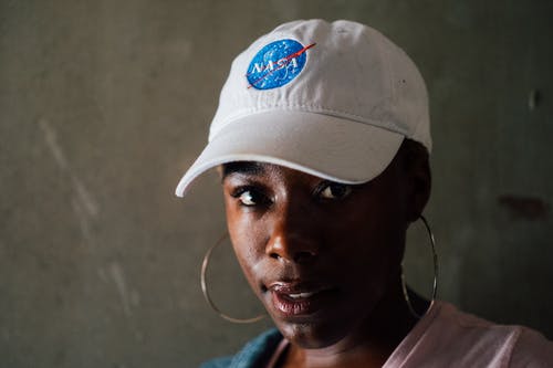 女人戴着箍耳环和美国国家航空航天局棒球帽 · 免费素材图片