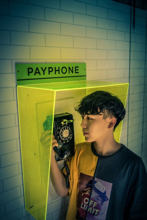 男孩抱着公用电话接收器 · 免费素材图片