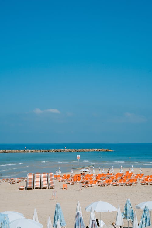 阴天在海滩附近的橙色躺椅 · 免费素材图片