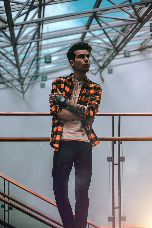 男子站在黄铜栏杆侧身看 · 免费素材图片