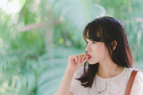 女人吸拇指手指附近绿树 · 免费素材图片