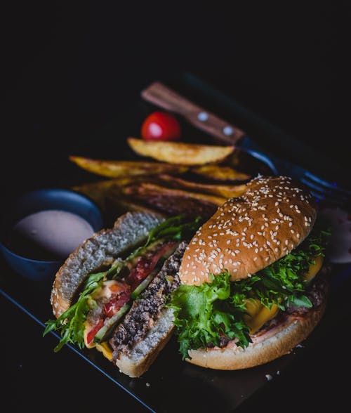 汉堡与绿叶蔬菜和奶酪在黑色印版上 · 免费素材图片