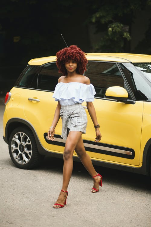 女人穿着白色的露肩女衬衫站在黄色菲亚特500升旁边 · 免费素材图片