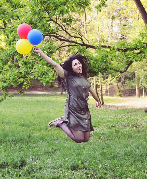 女人抱着四个气球跳 · 免费素材图片